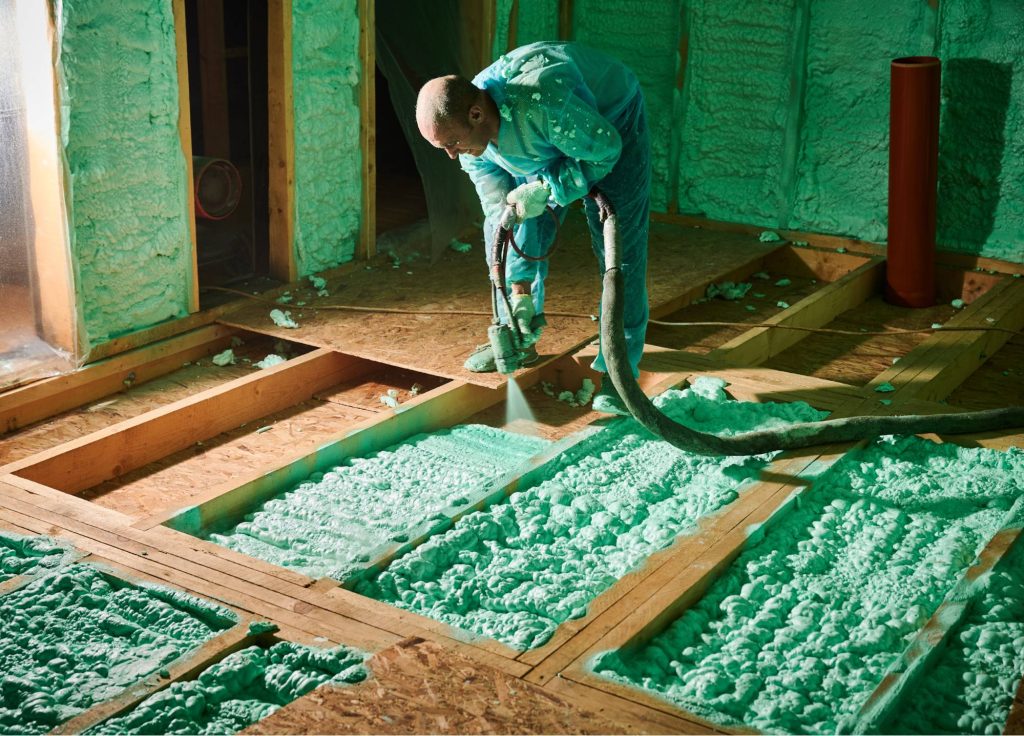 pracownik natryskujący piankę poliuretanową do izolacji domu